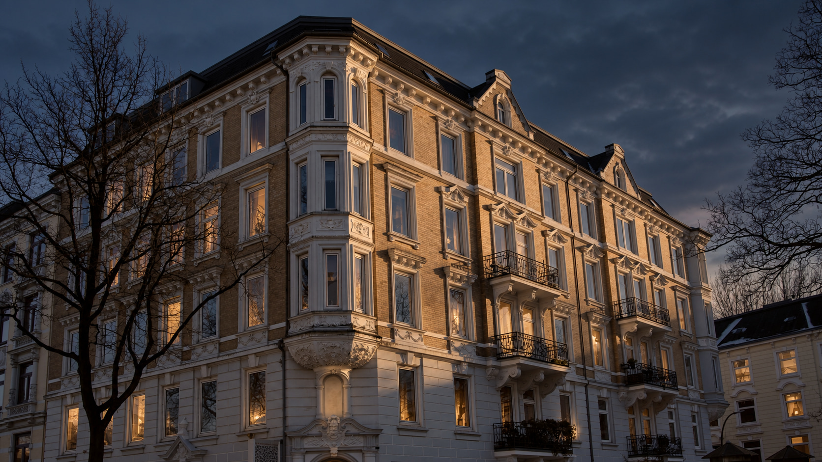 Historic corner façade with ornate details and warmly lit windows at dusk